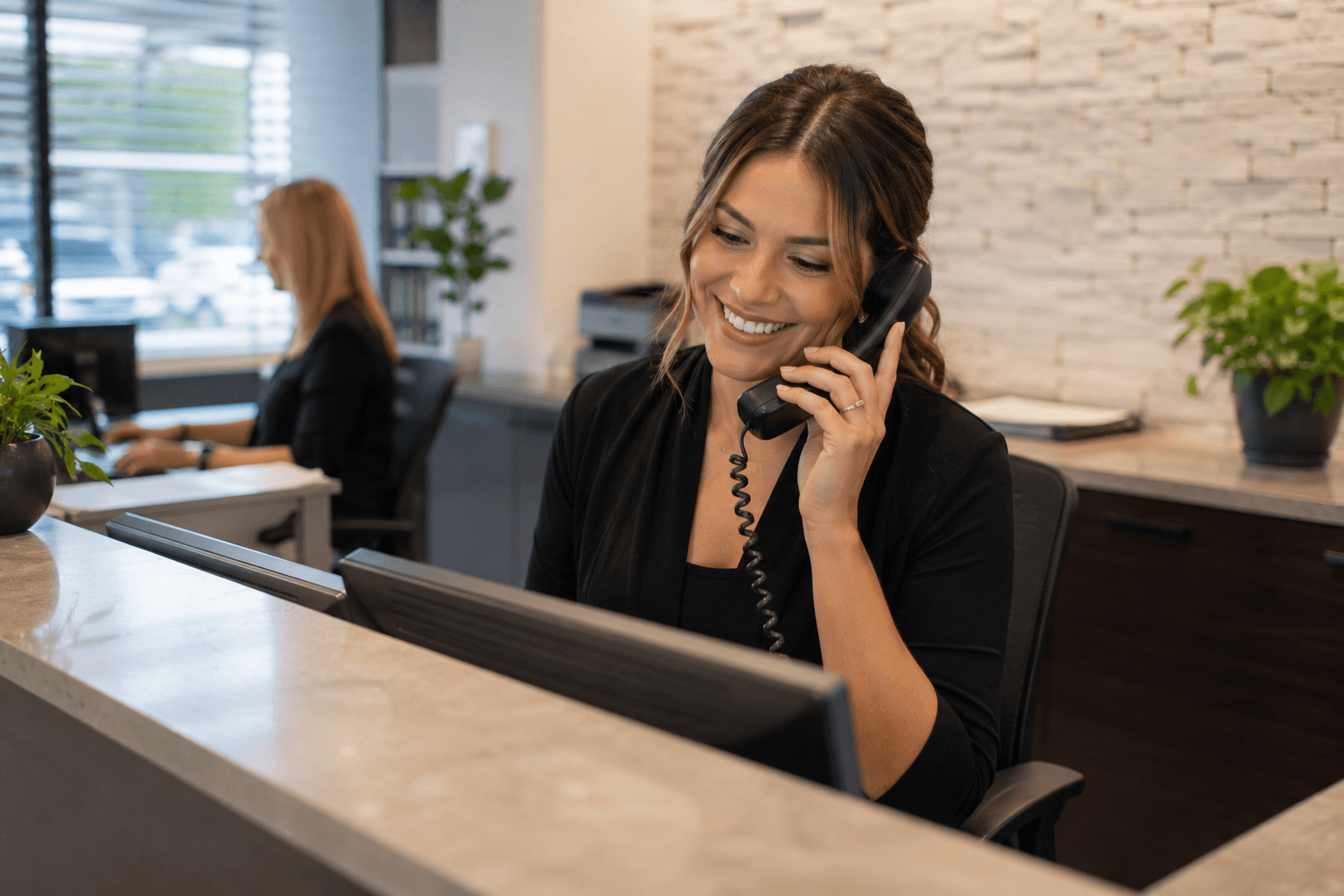 A friendly employee answering the phone at a small business front desk